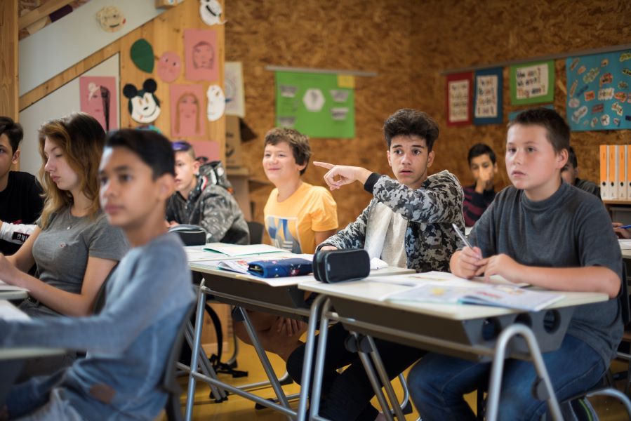 Kinder sitzen im Klassenraum und folgen dem Unterricht
