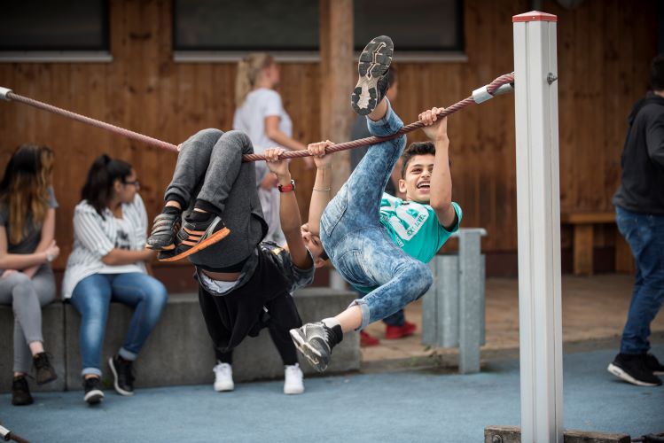 Kinder spielen an einem Kletterseil auf dem Schulhof