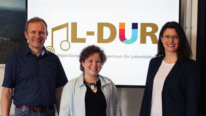 drei Personen stehen vor einem Bildschirm