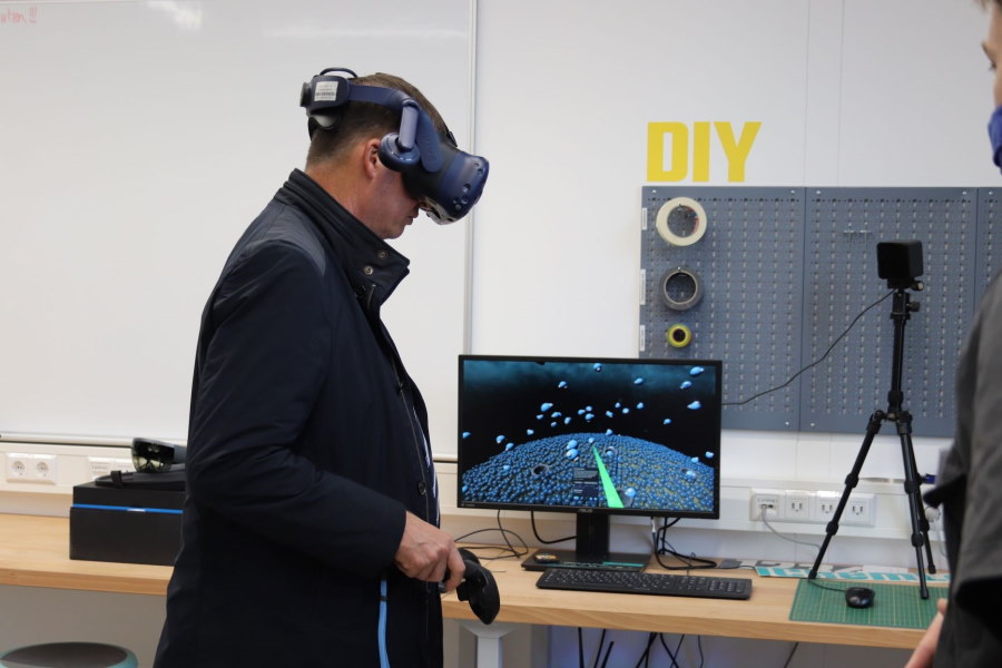 Im Medienlabor taucht MdB Axel Müller mit VR-Brille in die menschliche Zellstruktur ein.