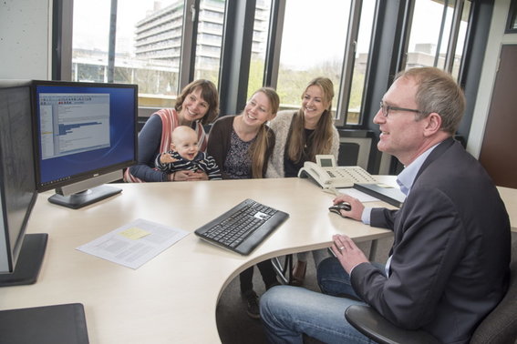 Drei Frauen, ein Baby und ein Mann schauen auf einen Monitor