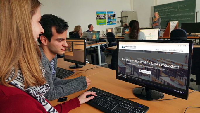 Eine junge Frau und ein junger Mann schauen in einen Laptop, der Lehrmaterial zeigt