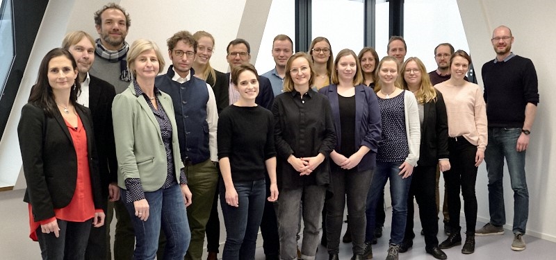 Eine Gruppe von jungen Frauen und Männern steht zusammen und schaut lächelnd in die Kamera.