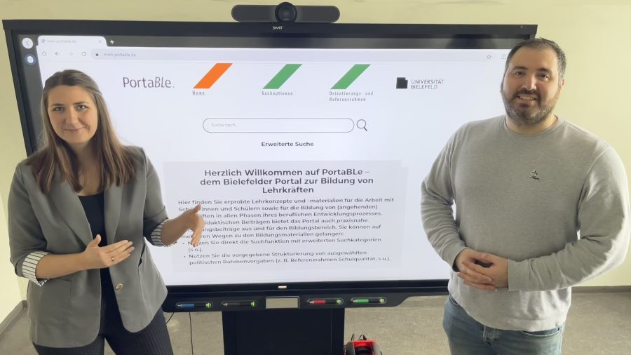 Im Hintergrund steht ein Smartboard auf dem die Startseite von PortaBLe zu sehen ist. Im Vordergrund stehen zwei Personen (Dr. Julia Schweitzer und Arash Haghani), die in die Kamera schauen und das Portal präsentieren.