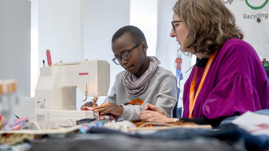 Ein Schüler sitzt an einer Nähmaschine an der Station „Lehr-Lern-Labor Textil“ am OLELA-Tag der offenen Tür an der Carl von Ossietzky Universität Oldenburg und wird von einer Betreuerin angeleitet.